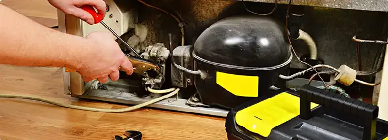 Refrigerator repair technician fixing the compressor and wiring in Spanish Fort, AL