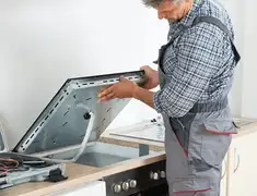 Appliance repair technician installing a built-in cooktop in Mobile, AL