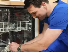 Dishwasher repair technician inspecting and servicing an open dishwasher in Mobile, AL