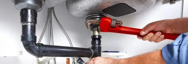 Garbage disposal repair technician tightening the sink drain and disposal connection in Mobile, AL