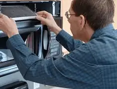 Appliance repair technician replacing a microwave vent filter in Mobile, AL