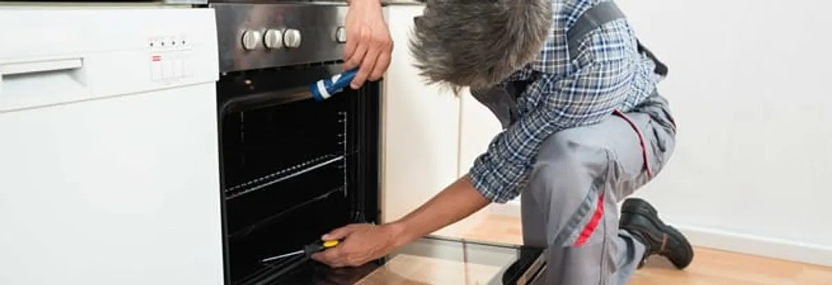 Oven repair technician inspecting and servicing an electric oven in Mobile, AL