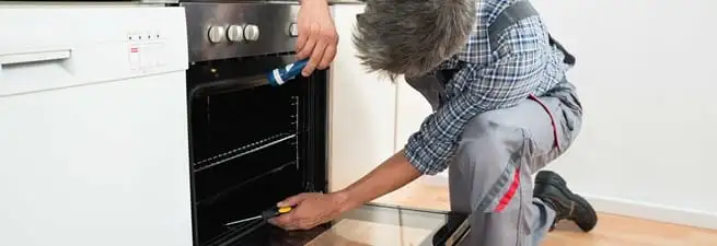 Oven repair technician inspecting and servicing an electric oven in Mobile, AL