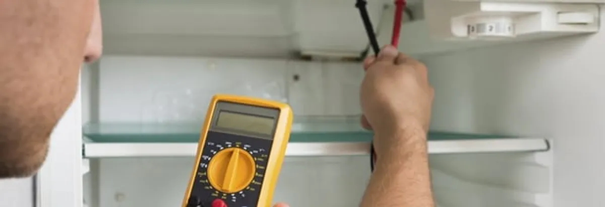 Refrigerator repair technician testing electrical components with a multimeter in Mobile, AL