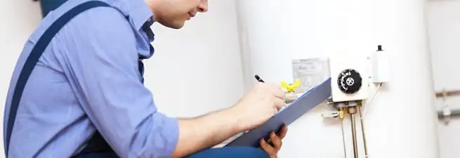 Water heater repair technician inspecting the unit and recording service notes in Mobile, AL