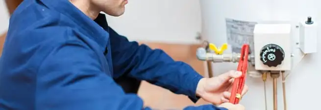 Water heater repair technician adjusting the temperature control and gas valve in Mobile, AL